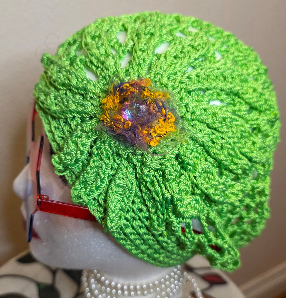Verde Bloom Hat side view with bloom — lime-green lattice openwork crochet cap on mannequin head